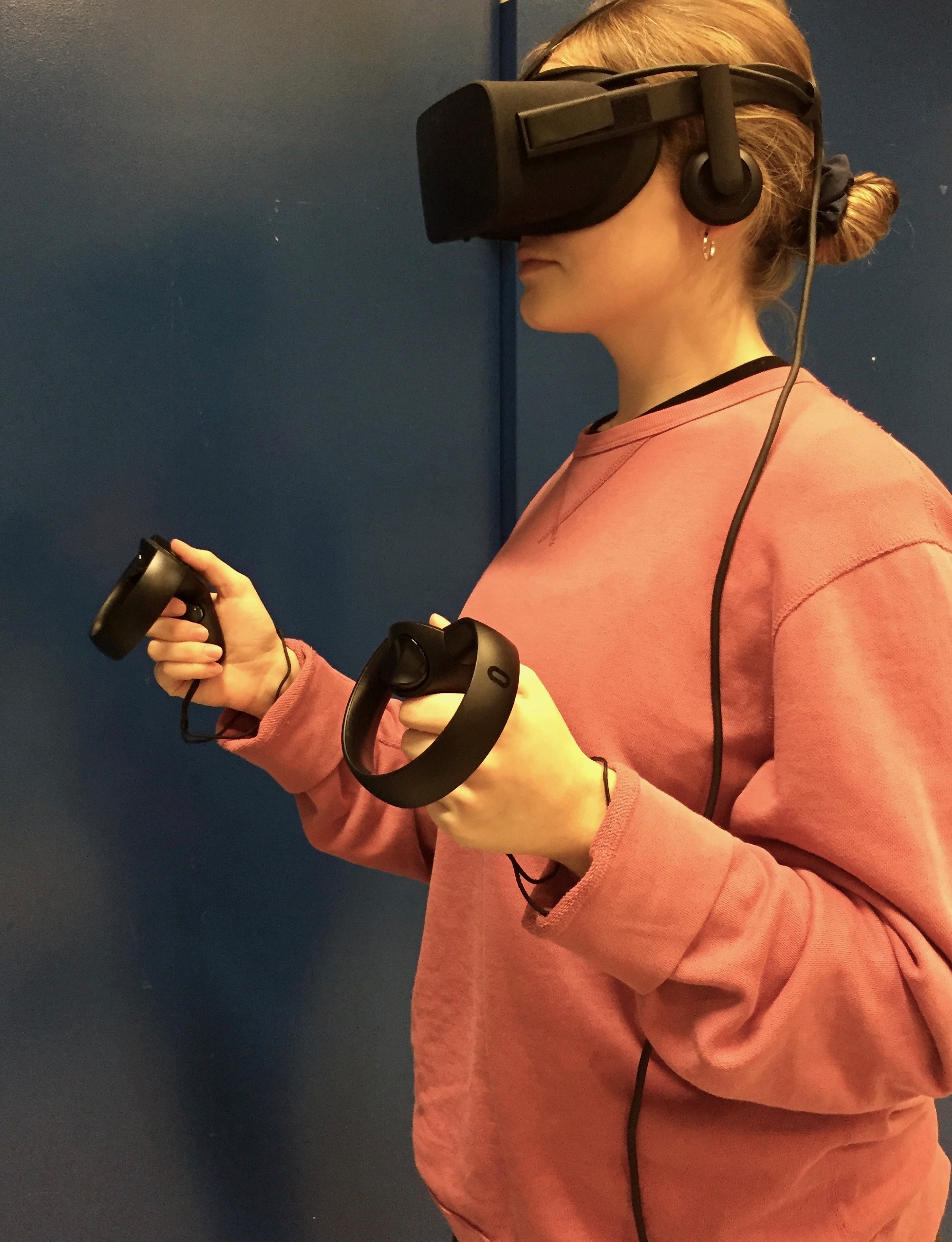 student wearing VR goggles and holding devices in hands
