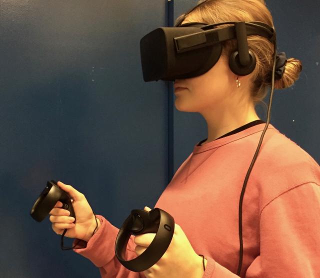 student wearing VR goggles and holding devices in hands